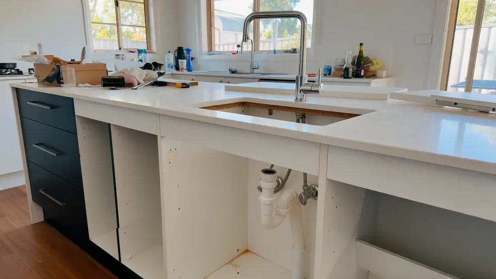 Kitchen renovation with sink plumbing connections beneath the benchtop
